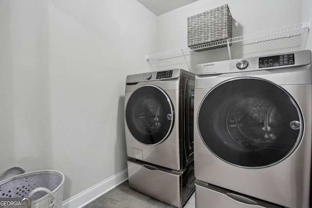 laundry area with light tile patterned floors, laundry area, washing machine and clothes dryer, and baseboards