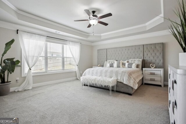 carpeted bedroom featuring baseboards, a raised ceiling, a ceiling fan, and crown molding