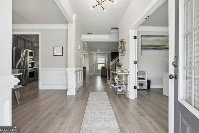 entryway with visible vents, a decorative wall, ornamental molding, wood finished floors, and stairs