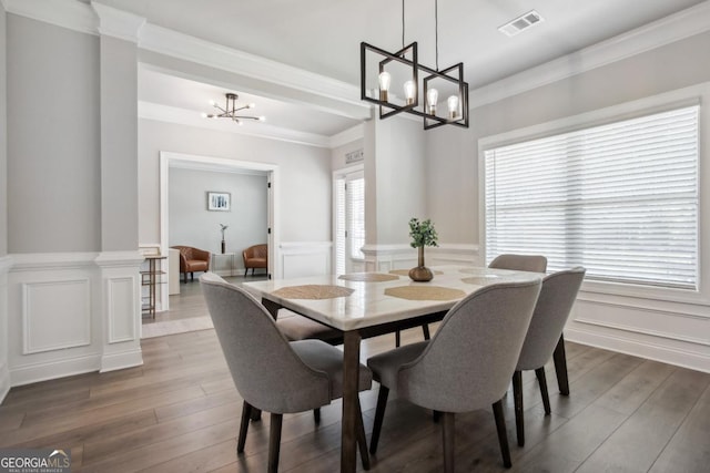 dining area with a wainscoted wall, crown molding, a chandelier, and wood finished floors