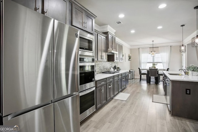 kitchen with stainless steel appliances, a sink, visible vents, ornamental molding, and backsplash