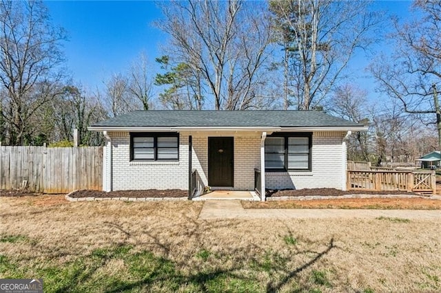 view of front of home with a front yard, brick siding, and fence