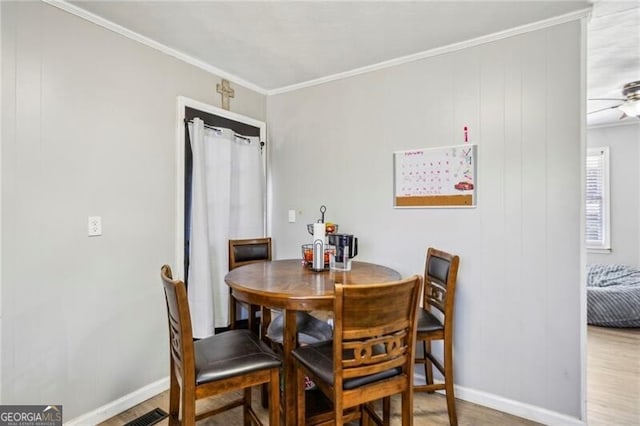 dining space featuring a ceiling fan, baseboards, ornamental molding, and wood finished floors