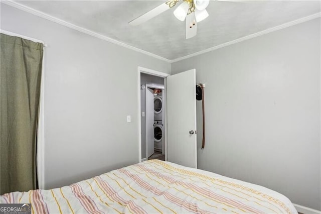 bedroom featuring ornamental molding, stacked washing maching and dryer, and a ceiling fan