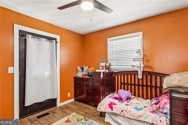 bedroom featuring baseboards, wood finished floors, visible vents, and a ceiling fan