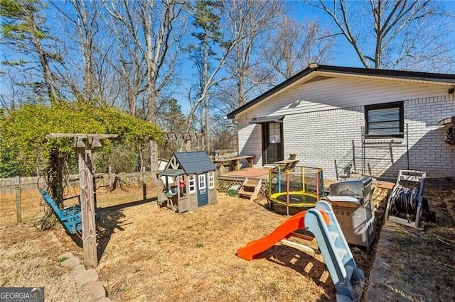 view of jungle gym featuring fence and an outdoor structure