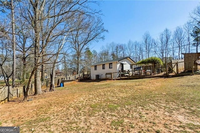 exterior space featuring a lawn, a wooden deck, and fence