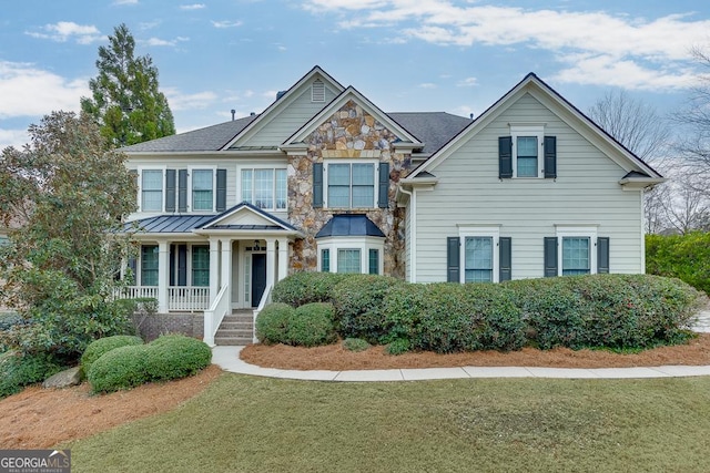 view of front of property featuring stone siding, a front lawn, and covered porch