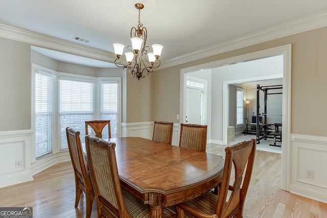 dining space with ornamental molding, visible vents, and light wood-style floors