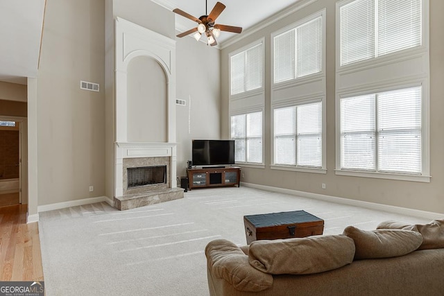 living area featuring baseboards, visible vents, a high ceiling, and a premium fireplace