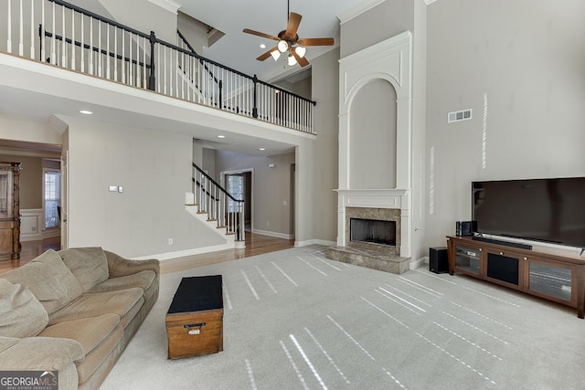 living room with baseboards, visible vents, ceiling fan, stairs, and a fireplace