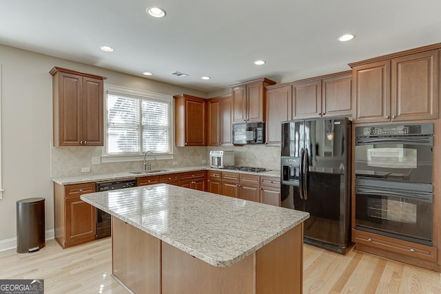 kitchen with black appliances, visible vents, light wood finished floors, and a sink