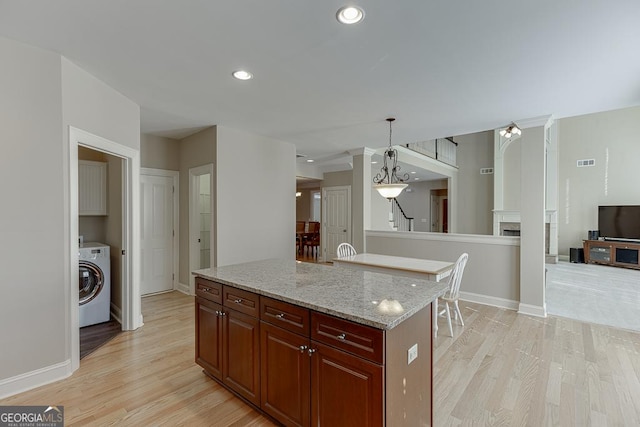 kitchen with washer / dryer, a fireplace, visible vents, and light wood finished floors