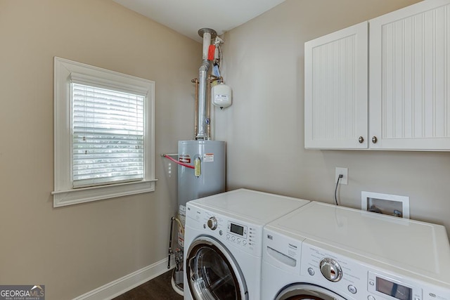 washroom featuring cabinet space, water heater, baseboards, and independent washer and dryer