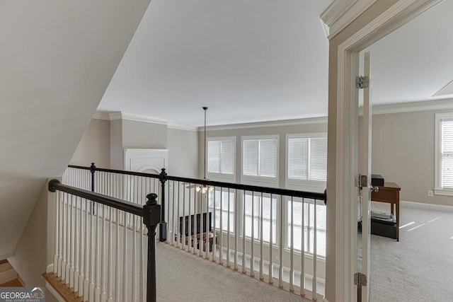 hallway featuring carpet floors, an upstairs landing, crown molding, and baseboards