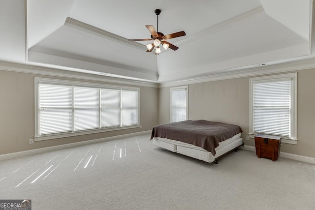 carpeted bedroom featuring baseboards, ceiling fan, a tray ceiling, and crown molding