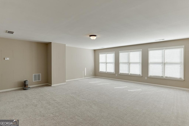 unfurnished room with visible vents, light carpet, and baseboards