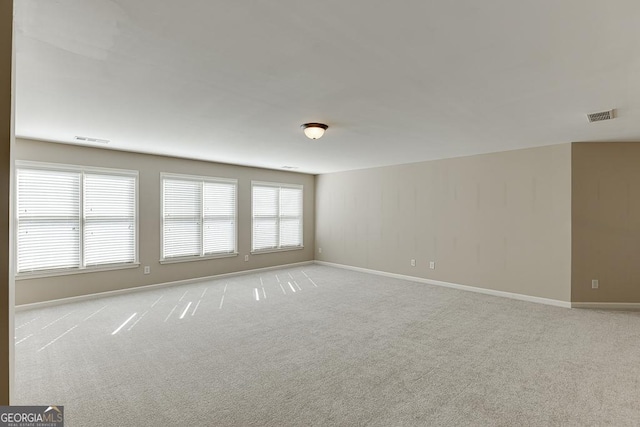 spare room featuring light carpet, baseboards, and visible vents