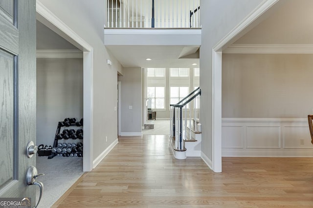 foyer featuring crown molding, stairway, a high ceiling, and wood finished floors