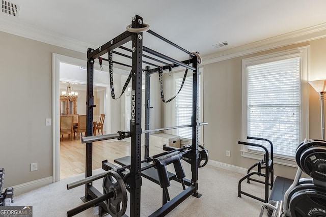 workout area with light carpet, visible vents, a wealth of natural light, and ornamental molding