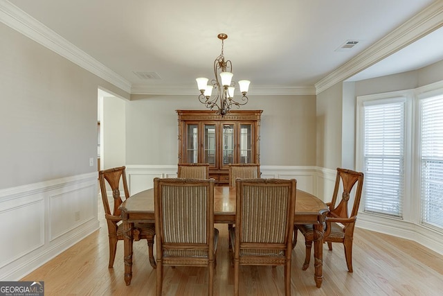 dining area featuring crown molding, light wood finished floors, visible vents, and a notable chandelier