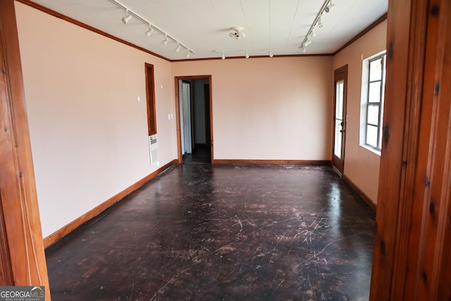 empty room featuring baseboards, concrete floors, rail lighting, and crown molding