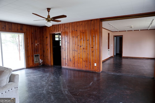 unfurnished living room with track lighting, plenty of natural light, and wooden walls