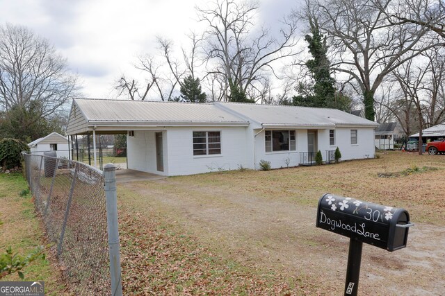 ranch-style home featuring metal roof, an attached carport, fence, and driveway