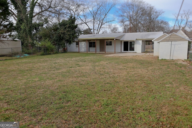 view of front facade with an outbuilding, a patio, metal roof, a fenced backyard, and a front lawn