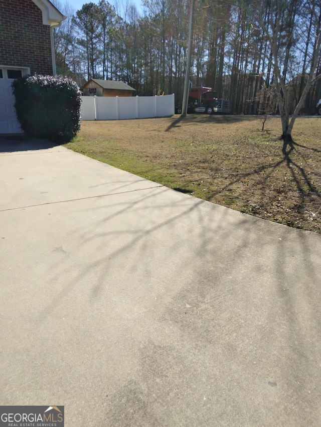 view of yard featuring driveway, a garage, and fence