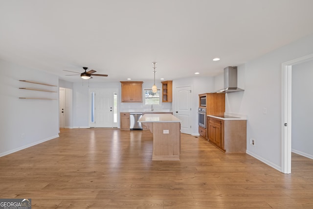 kitchen with stainless steel appliances, light wood-style floors, a sink, a kitchen island, and wall chimney exhaust hood