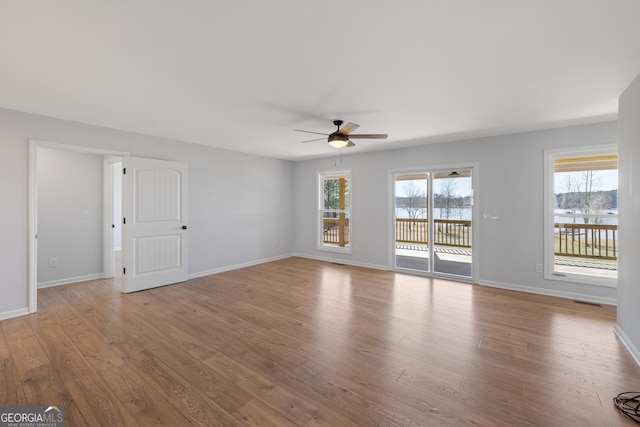 unfurnished living room featuring wood finished floors, a ceiling fan, and baseboards