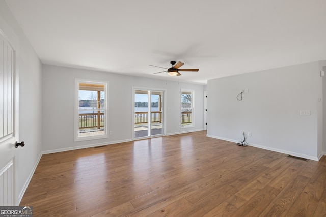 unfurnished living room featuring visible vents, plenty of natural light, and wood finished floors