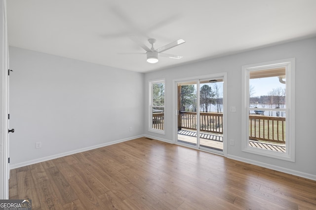 empty room featuring wood finished floors, a ceiling fan, and baseboards