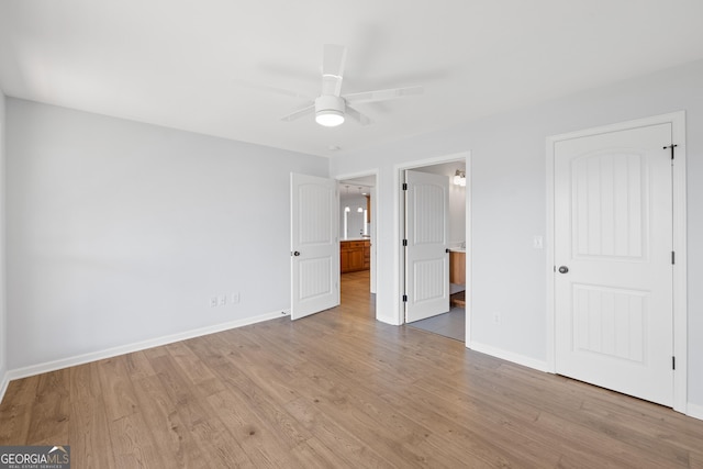 unfurnished bedroom featuring ensuite bathroom, ceiling fan, wood finished floors, and baseboards