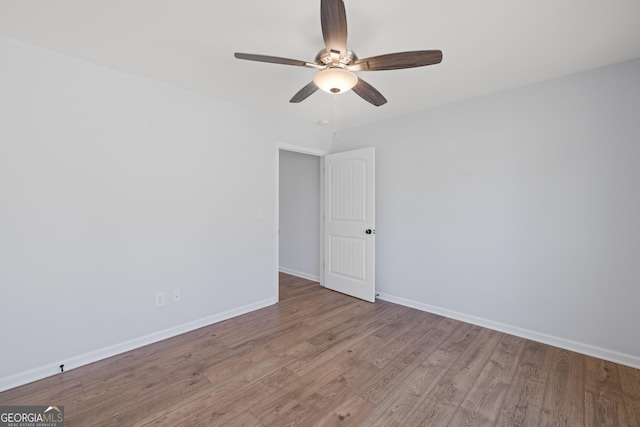 empty room featuring ceiling fan, baseboards, and wood finished floors