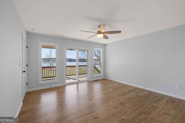 empty room featuring a ceiling fan, baseboards, and wood finished floors