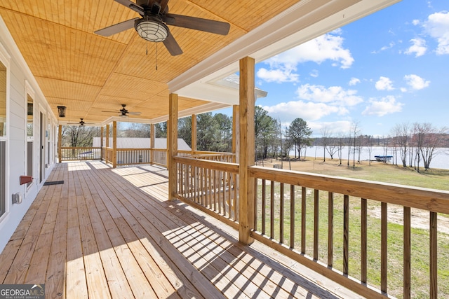 deck with a water view, ceiling fan, and a yard