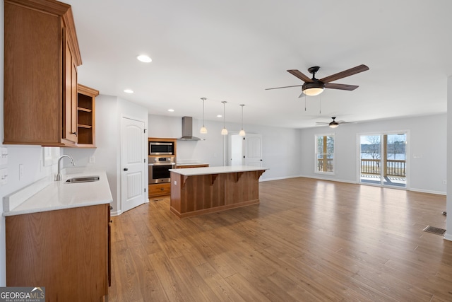 kitchen with a kitchen island, a sink, appliances with stainless steel finishes, wall chimney exhaust hood, and open shelves