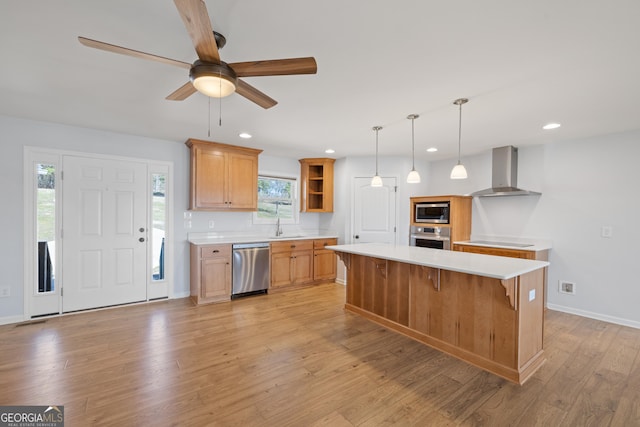 kitchen with open shelves, light countertops, appliances with stainless steel finishes, wall chimney range hood, and light wood-type flooring