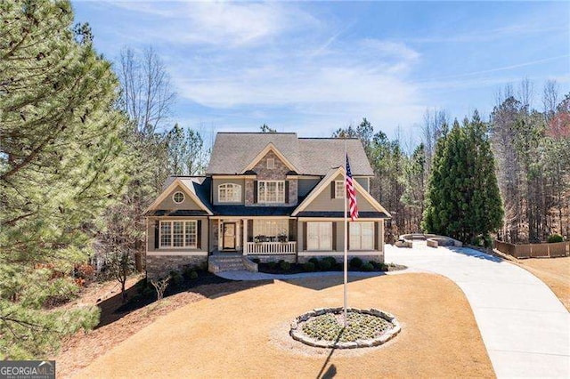 view of front of property with a porch, stone siding, and driveway