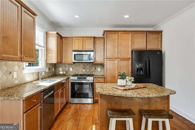 kitchen with crown molding, stainless steel appliances, decorative backsplash, a sink, and a kitchen island