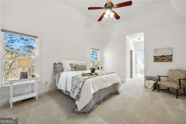 carpeted bedroom with a high ceiling, ceiling fan, and baseboards