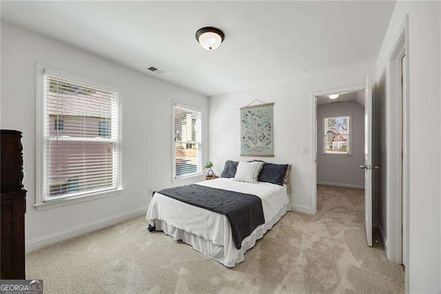 bedroom with light carpet, multiple windows, and baseboards