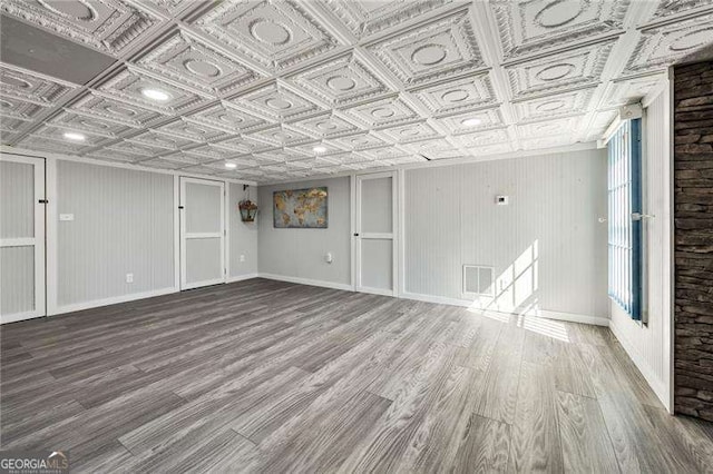 unfurnished room featuring visible vents, wood finished floors, an ornate ceiling, and baseboards