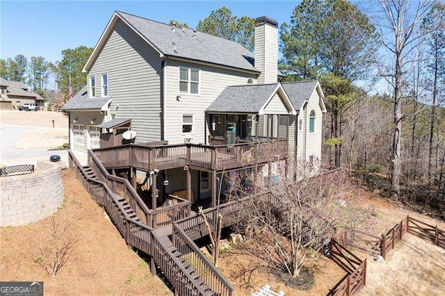 rear view of house with stairs, a chimney, and a deck