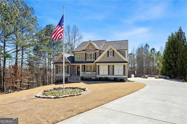 craftsman-style house with driveway, a front lawn, and a porch