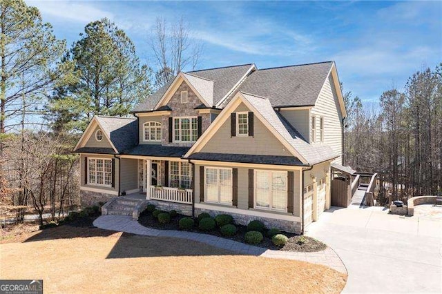 view of front of home with stone siding, covered porch, and concrete driveway