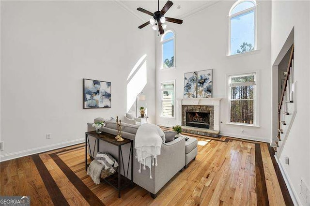 living room with a stone fireplace, wood-type flooring, and baseboards