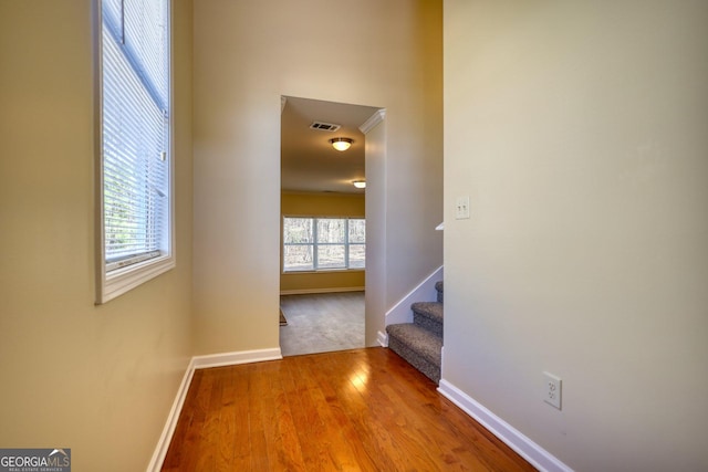 corridor with stairs, wood finished floors, visible vents, and baseboards